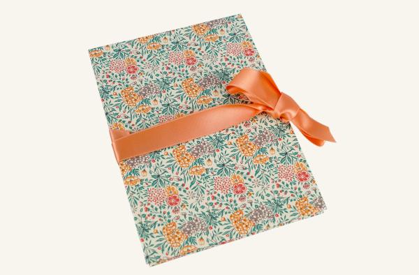 small photo album with stylized orange-red flowers and red ribbon